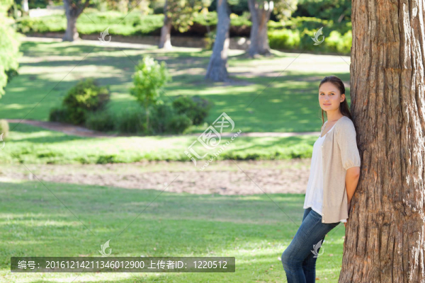 在公園里倚著一棵樹的女人