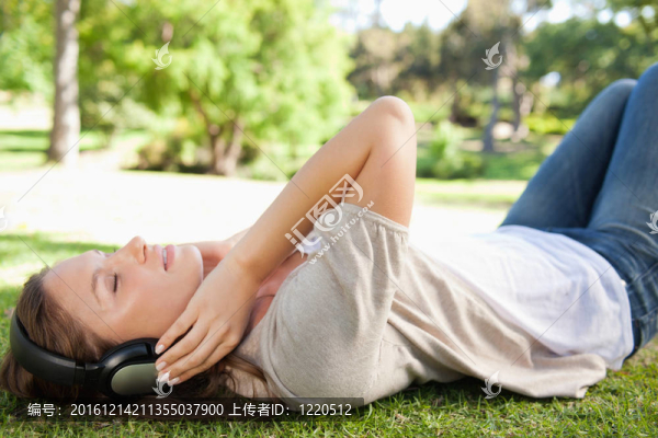 女人躺在草地上一邊欣賞音樂
