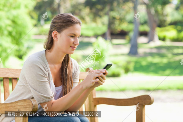 女子在公園長椅上讀短信