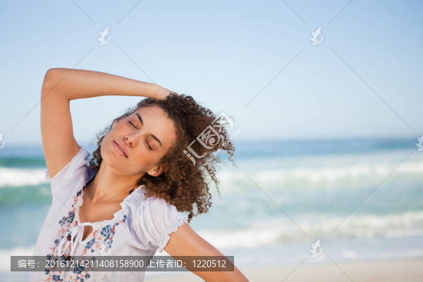 年輕女子站在海灘上閉上眼睛