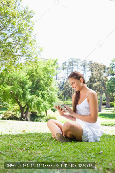 一位面帶微笑的婦女在草坪上用平板電腦