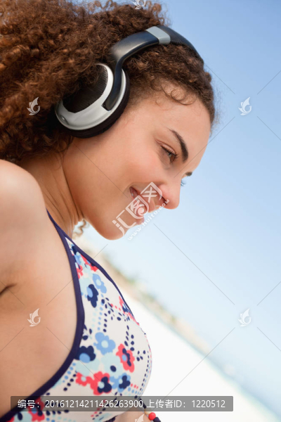 在比基尼聽音樂在沙灘上漂亮的年輕女人