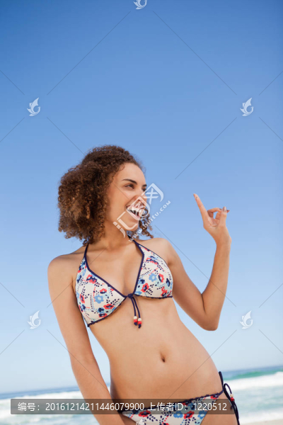 年輕女子站在沙灘上，手指著微笑