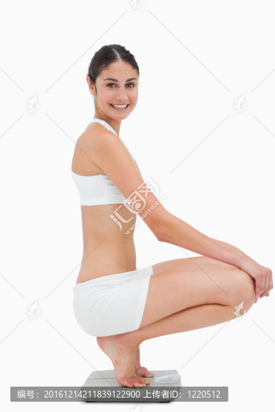 苗條的年輕女子坐在秤上