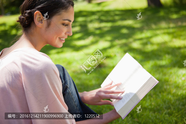 女人坐在草地上看書