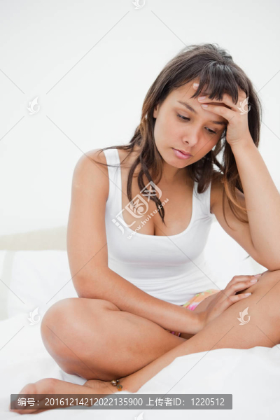 悲傷的年輕女人在睡衣上她的床