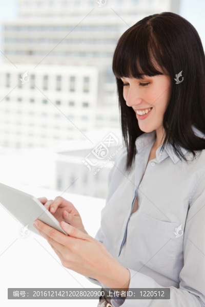 一個快樂的女人在辦公室使用她的平板電腦