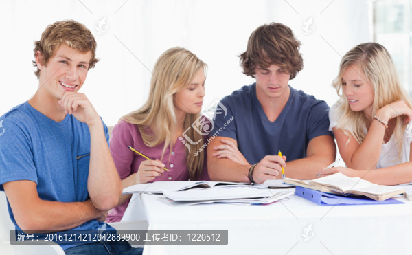 一群學(xué)生坐在一起，因?yàn)樗麄兌紝W(xué)習(xí)一個(gè)微笑，看著相機(jī)