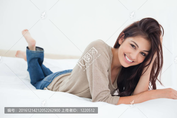 一個女人躺在床上，腿微微抬起，手放在頭發(fā)上。
