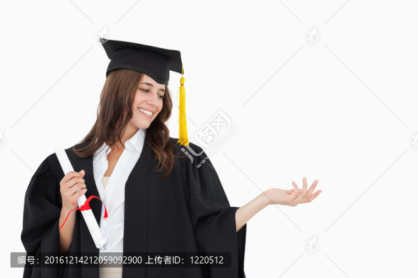一個(gè)女人看著她張開(kāi)的手，微笑著拿著另一只手的學(xué)位