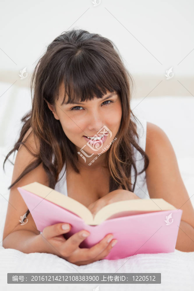 一個(gè)面帶微笑的年輕女人在讀一本書(shū)
