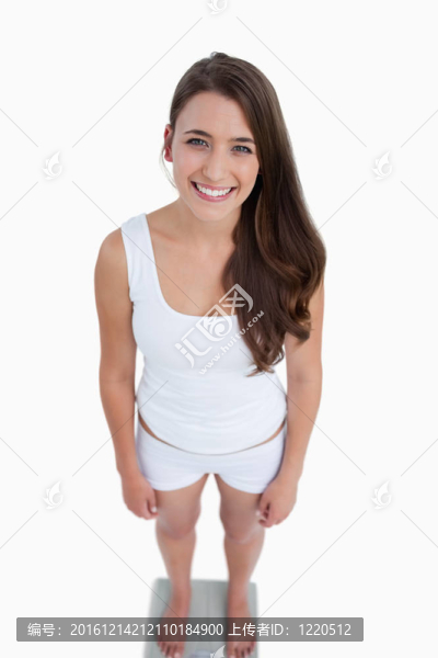 微笑的女人看著相機站在秤上