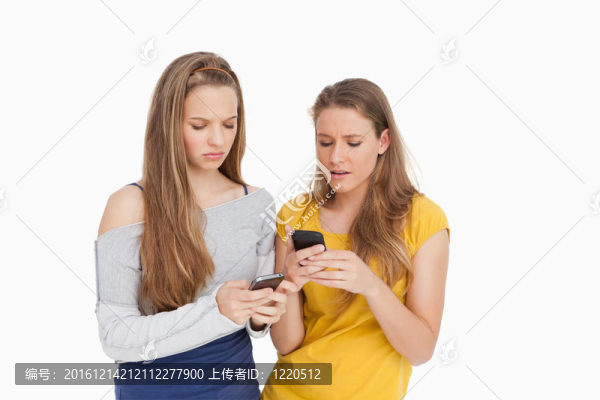 兩個(gè)年輕女子皺著眉頭，看著自己的手機(jī)