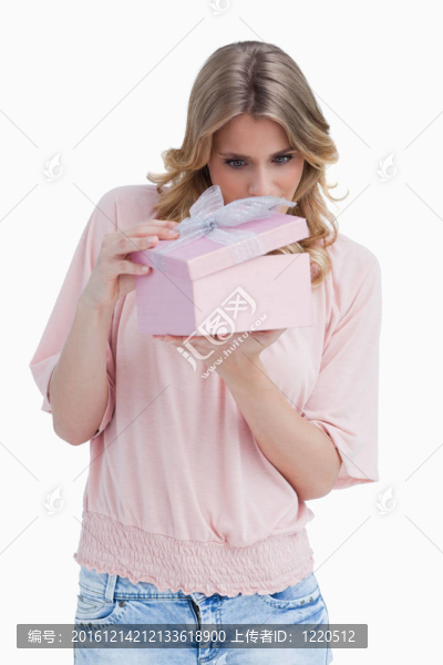 好奇的年輕女子一邊打開禮物一邊拿著
