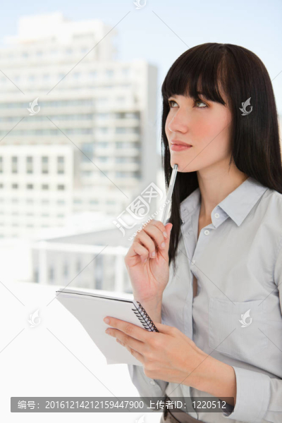 一個女人用筆記本和筆在下巴上想