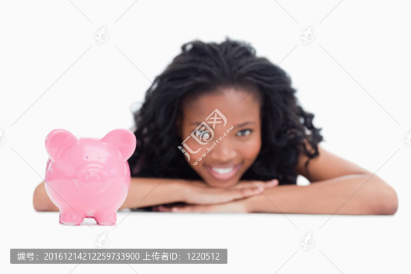 一個年輕的微笑女孩在一個白色的背景下在她的手上放著一個存錢罐