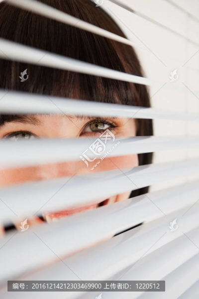 一個面帶微笑的女人透過她的窗簾