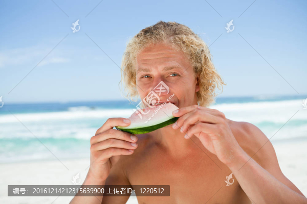 年輕人在海邊吃一塊西瓜