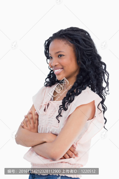 一個(gè)年輕的微笑的女人雙臂交叉，遠(yuǎn)離相機(jī)