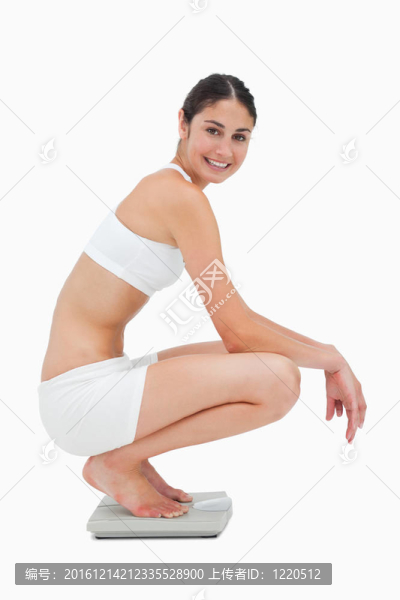 苗條的年輕女子微笑著坐在天平上