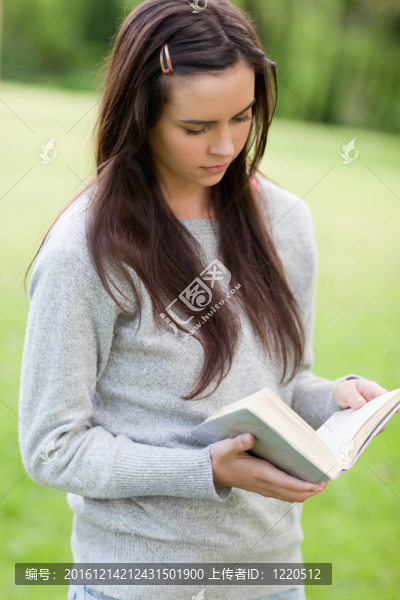 一個嚴(yán)肅的年輕女子站在公園里看書