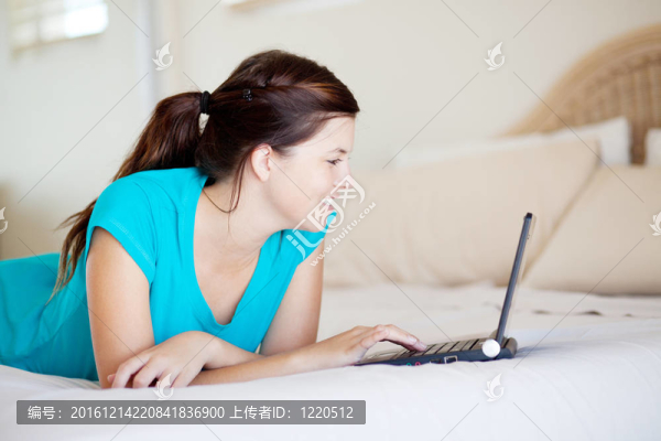 在床上使用筆記本電腦的少女