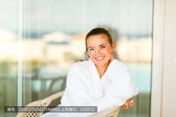 可愛的微笑的女人在浴袍坐在露臺的肖像
