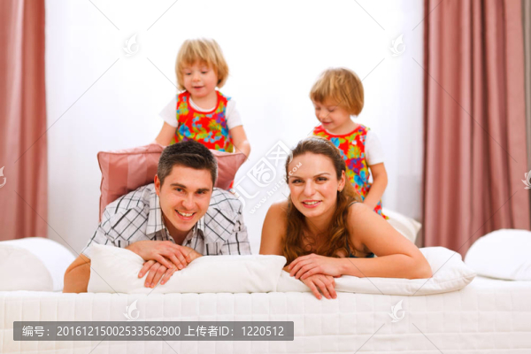 兩個面帶微笑的雙胞胎女兒坐在父母的背上