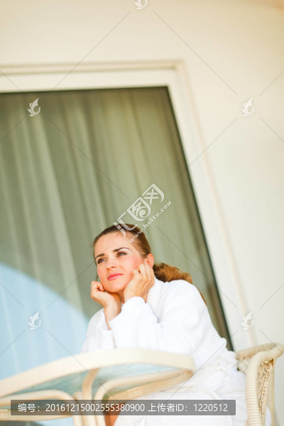 在浴袍坐在桌邊的年輕女子在陽臺(tái)