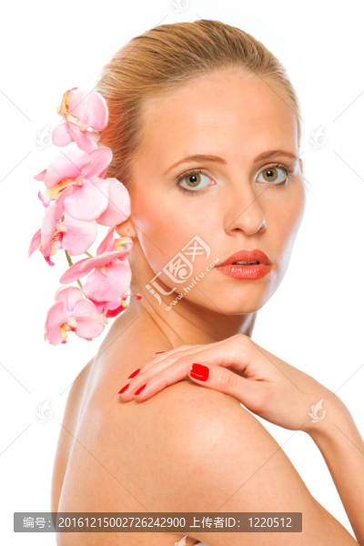 年輕漂亮的女人用粉紅色的蘭花在手上握著肩上的白色