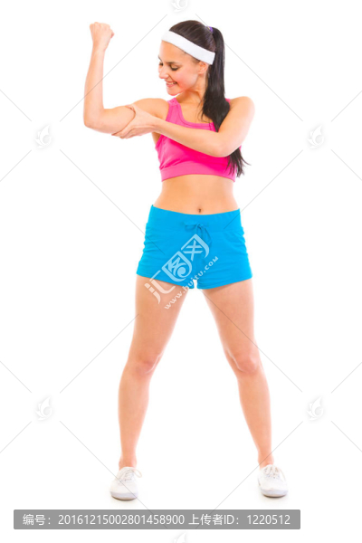 穿著運動服的快樂女孩的全長肖像在白色上檢查她的肌肉