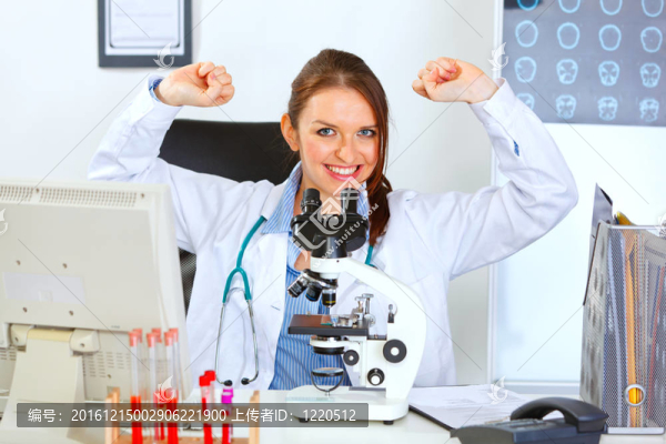 微笑的女醫(yī)生坐在實驗室里歡慶成功