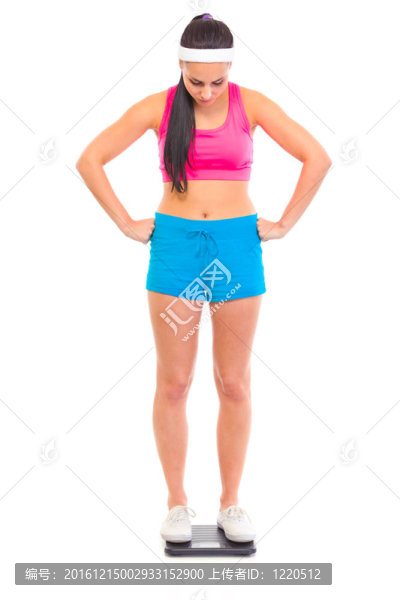 不滿她的體重年輕女孩站在地板上的規(guī)模孤立的白色