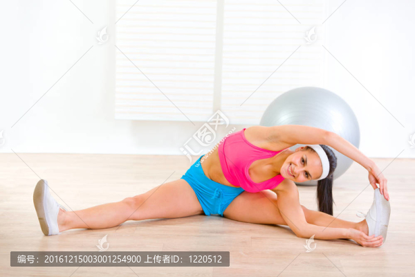 微笑靈活健身女性在客廳地板上做體操