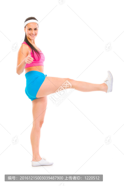 全尺寸的微笑健身女孩的畫像，抬起腿顯示拇指上孤立的白色