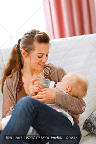 年輕的母親坐在沙發(fā)上喂嬰兒