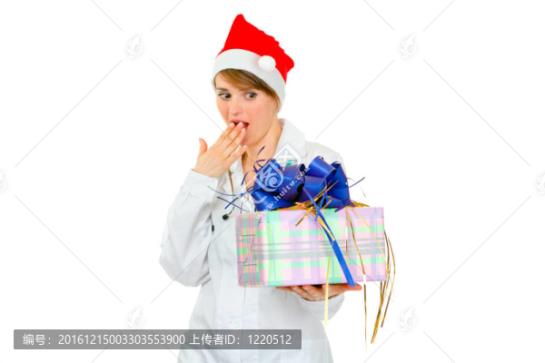 驚訝的醫(yī)生在Santa的女人帽子看著現(xiàn)在的盒子上孤立的白色