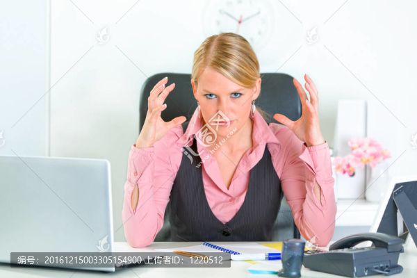 憤怒的現(xiàn)代商業(yè)女性坐在辦公桌前，雙手靠近頭部