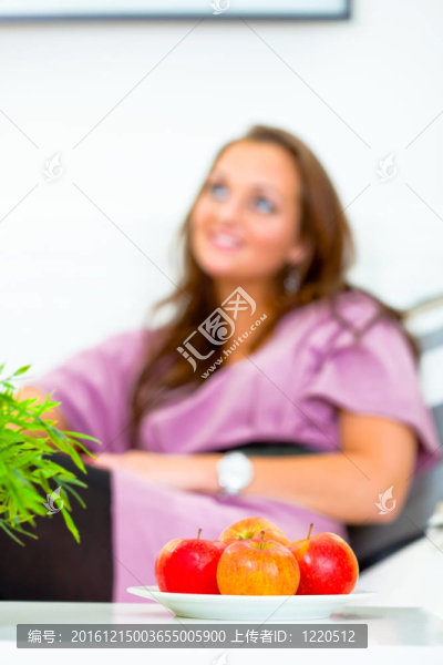水果拼盤上桌，微笑的女人在家里坐沙發(fā)背景