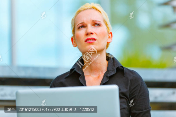 憂郁的女人坐在樓梯在現代商業(yè)辦公樓和使用筆記本電腦