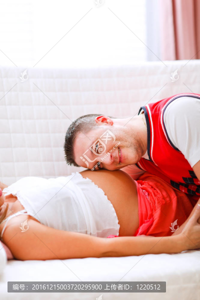 年輕的丈夫聽他懷孕的妻子的肚子特寫