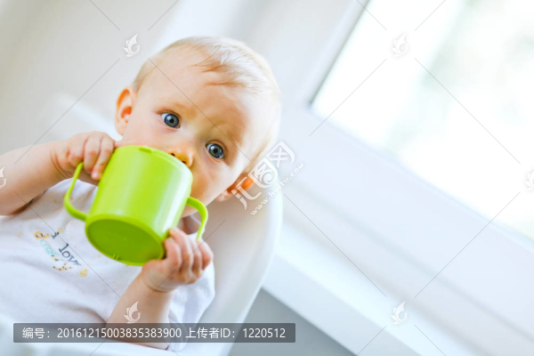 漂亮的小女孩坐在椅子上喝著嬰兒杯