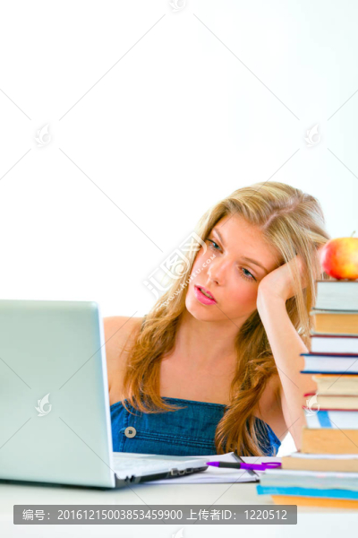 無聊的女孩坐在桌子上看著筆記本電腦