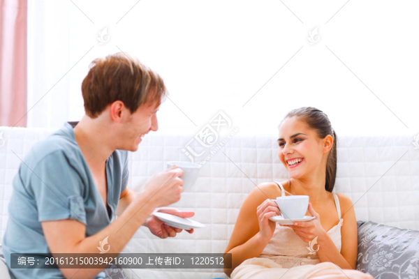 年輕夫婦坐在沙發(fā)上喝咖啡