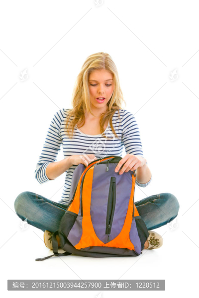 十幾歲的女孩坐在地板上和搜索的東西在書包白色隔離