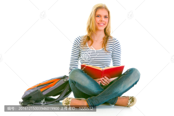 微笑的女孩坐在地板上，用背包閱讀教科書白色隔離