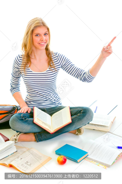 微笑的女孩坐在地上在教科書和指向角白色隔離