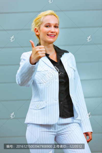 站在辦公樓微笑著現(xiàn)代商業(yè)女性豎起大拇指手勢(shì)