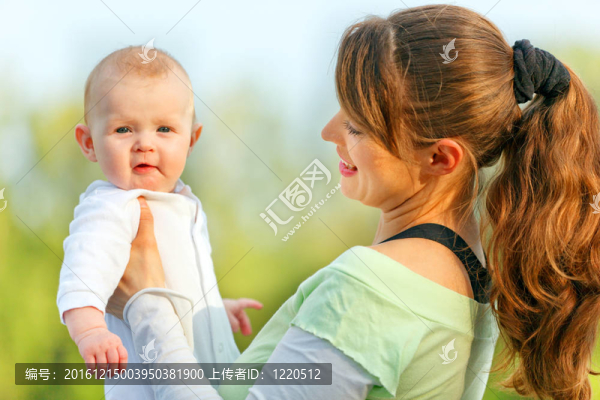 微笑的年輕母親在夏天抱著驚訝的嬰兒