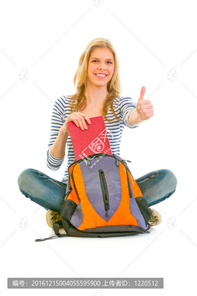 坐在地板上笑的女孩取書從書包和豎起了大拇指手勢白色隔離